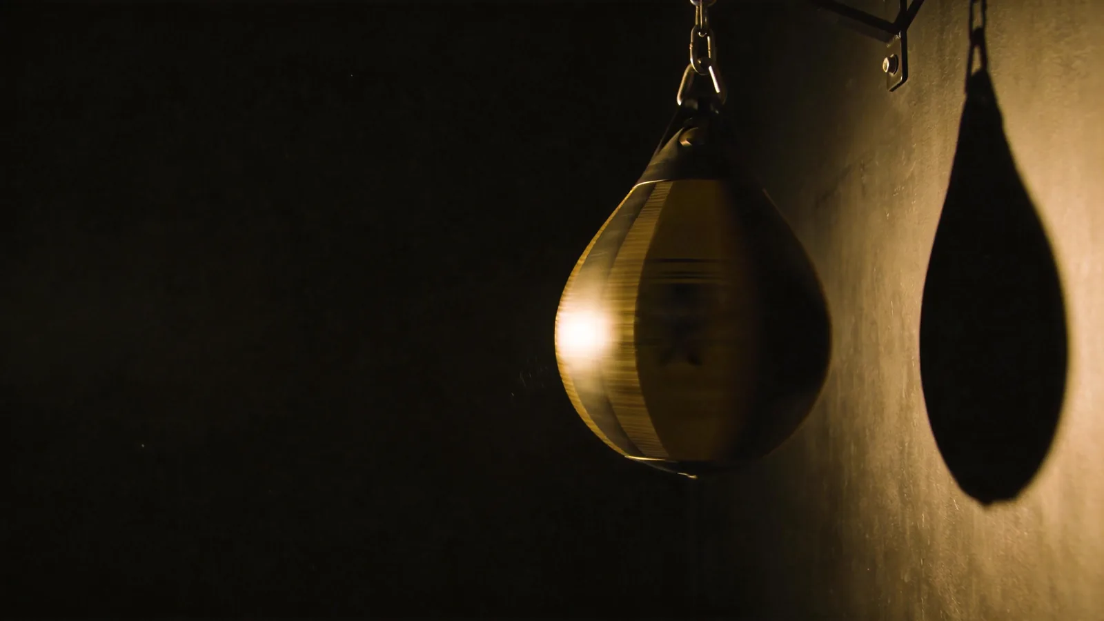 A speed bag mid-swing under a single gym light